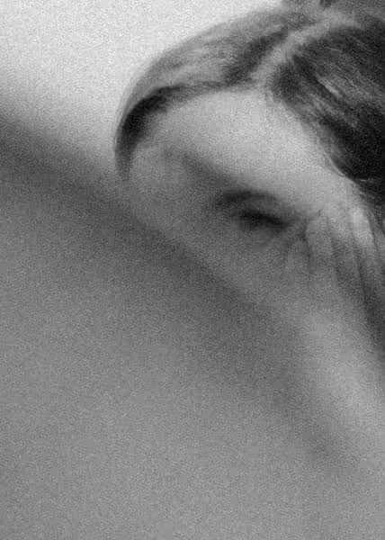 a woman looking behind a shoulder showing only one eye