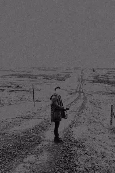 faceless man standing on a long stretch of road in Iceland