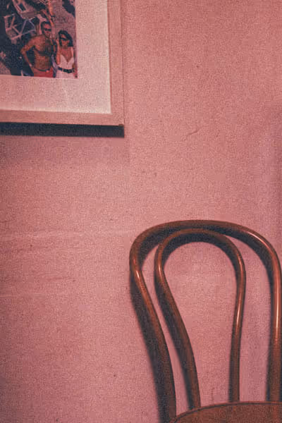 a chair in a pink room under a photo of a couple on vacation