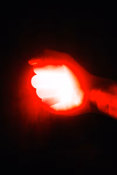 grainy red hand holding red light in a fist