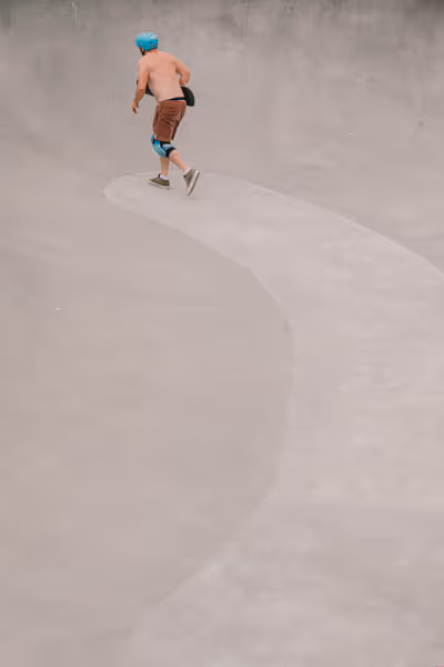 Skateboarder with blue helmet in the distance running for the lip of a pool in Venice Beach
