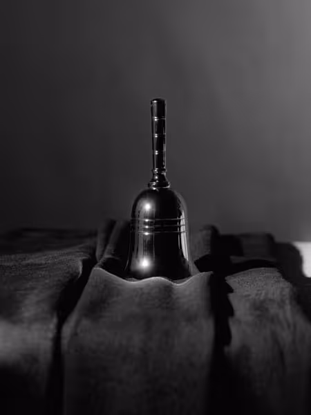 A small metallic hand bell on a velvet cloth