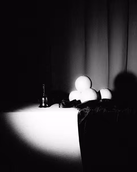 A handbell and stack of oranges are overexposed by a spotlight