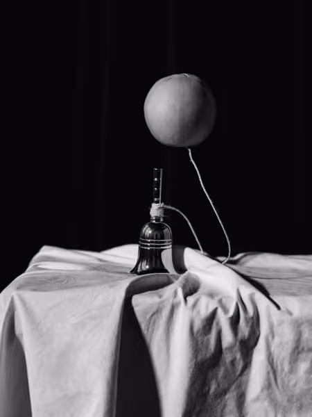 A hand bell attached to a floatig orange on a string