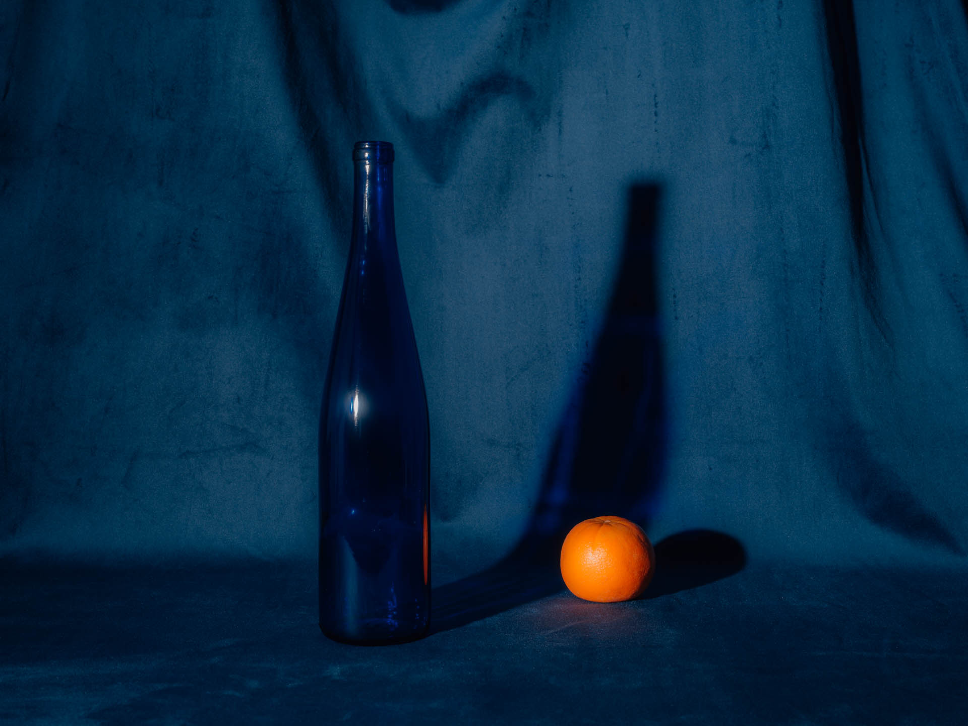 An orange with a blue bottle on blue velvet