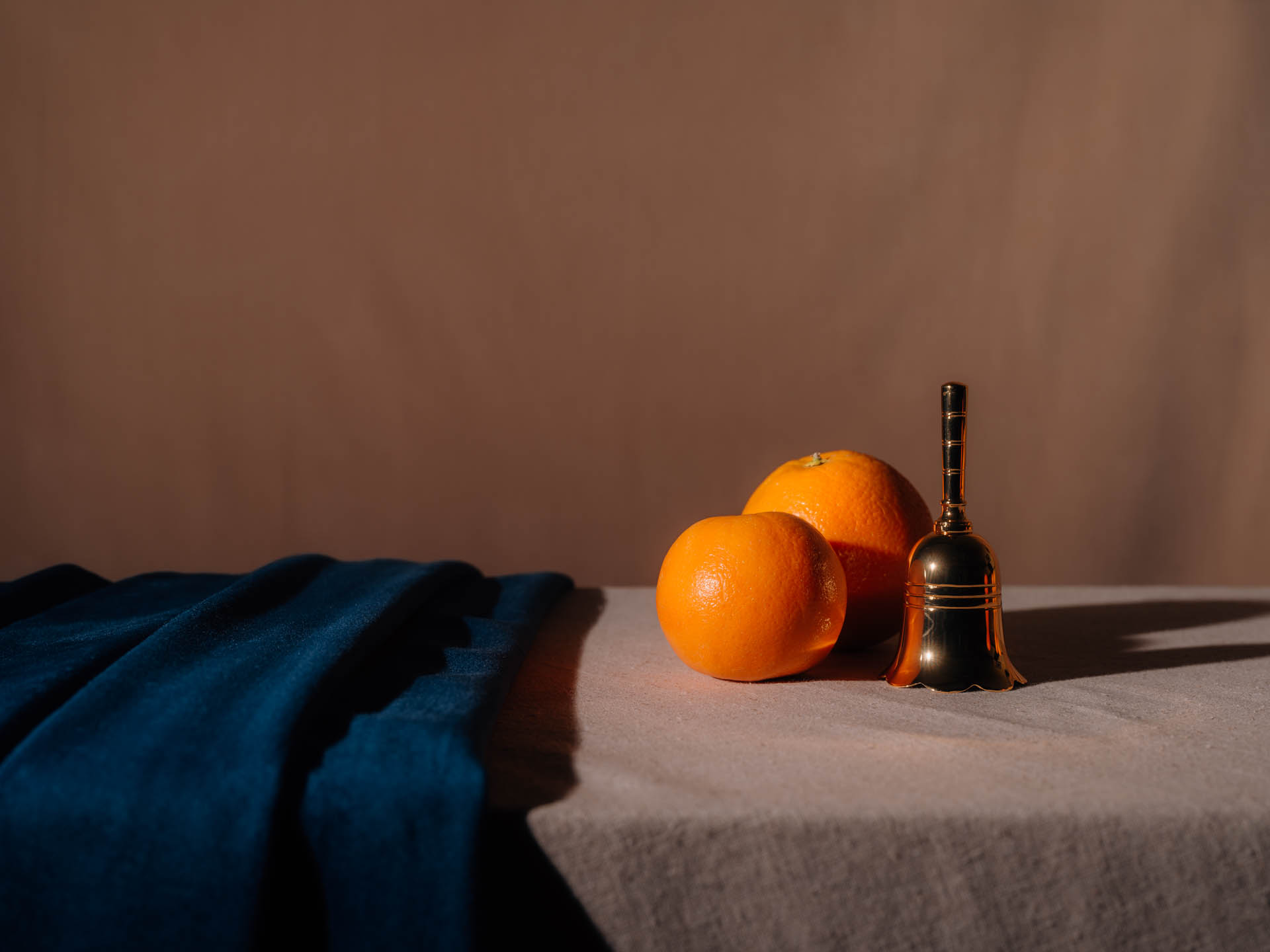 Two oranges with a small bell and blue velvet
