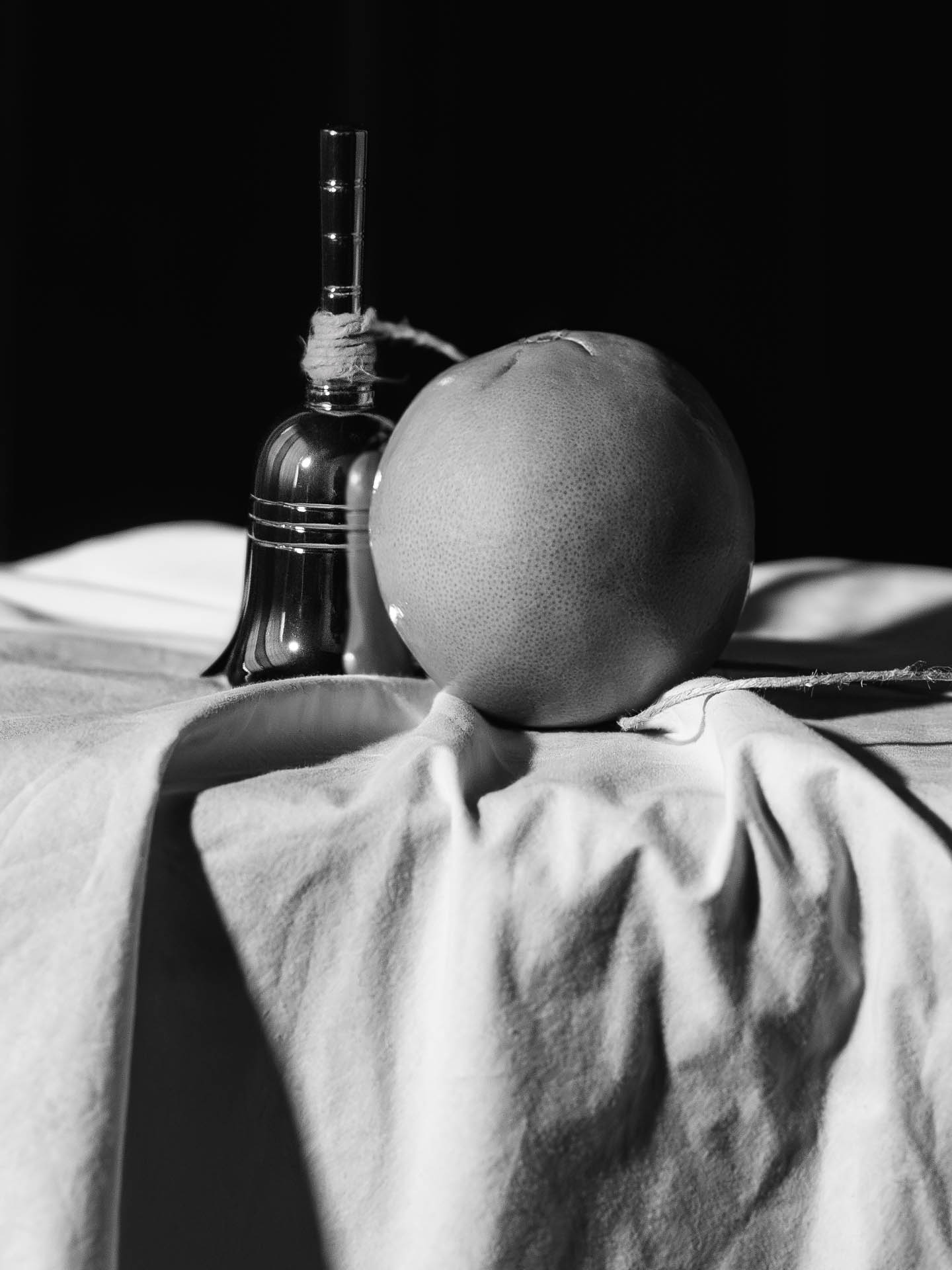 A hand bell and an orange connected by a string