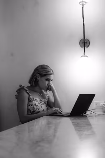 a woman looking annoyed or tired while on her laptop at a bar