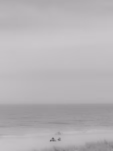A couple at the beach on a rainy day with an umbrella in black and white