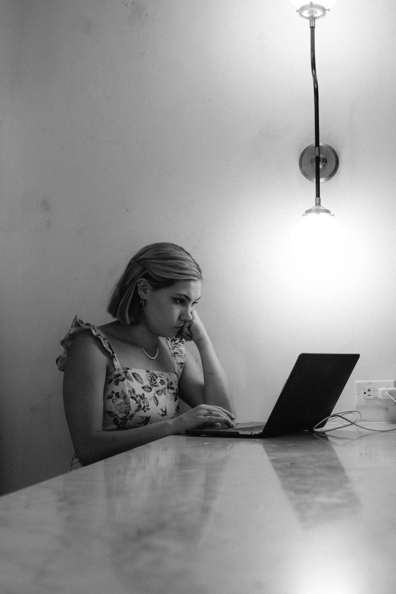 a woman looking annoyed or tired while on her laptop at a bar