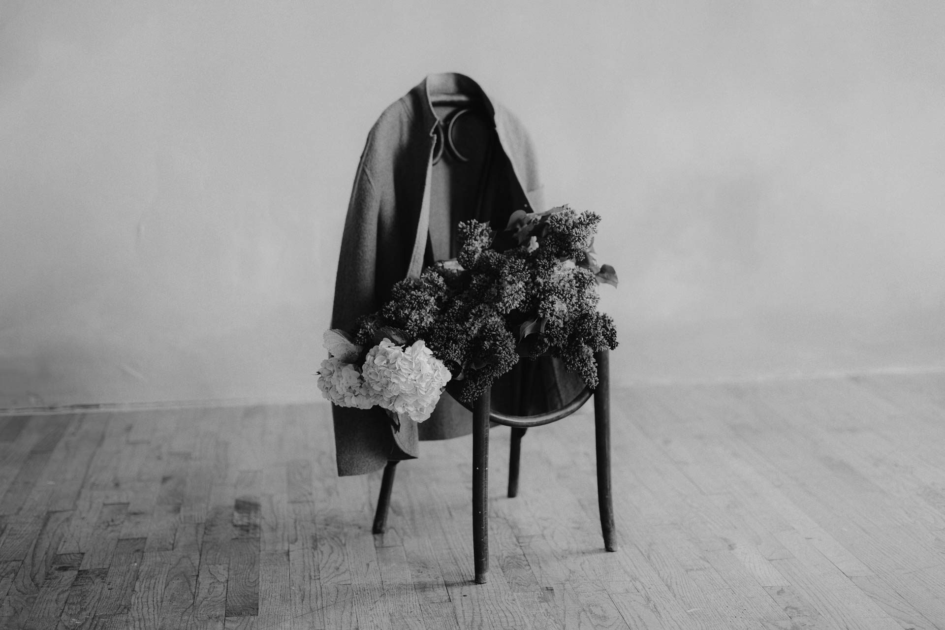 lilacs and hydrangeas flower bouquet on chair with felted jacket. black and white.