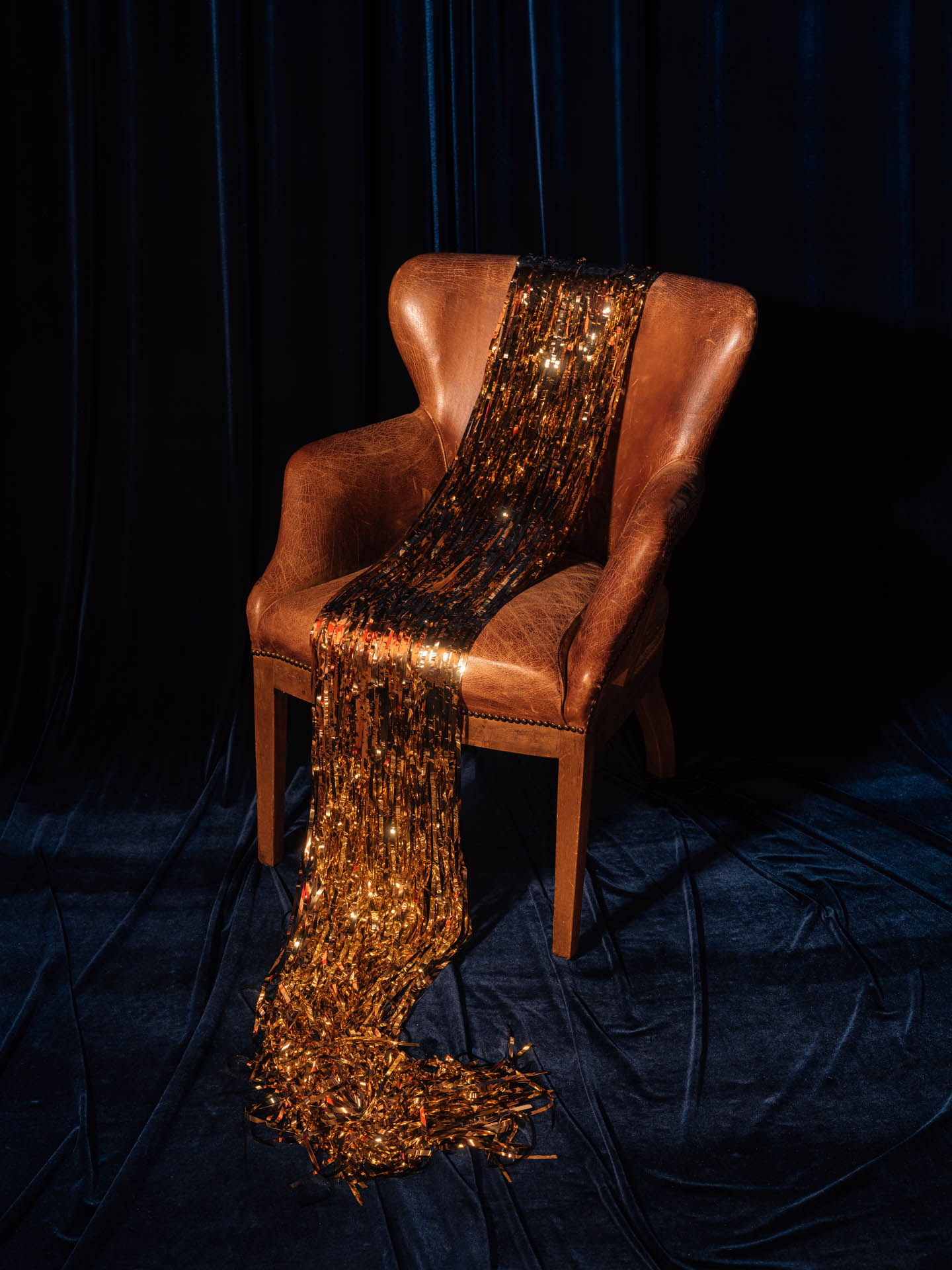 a brown leather chair with gold tinsel draped on it in the shape of a dress