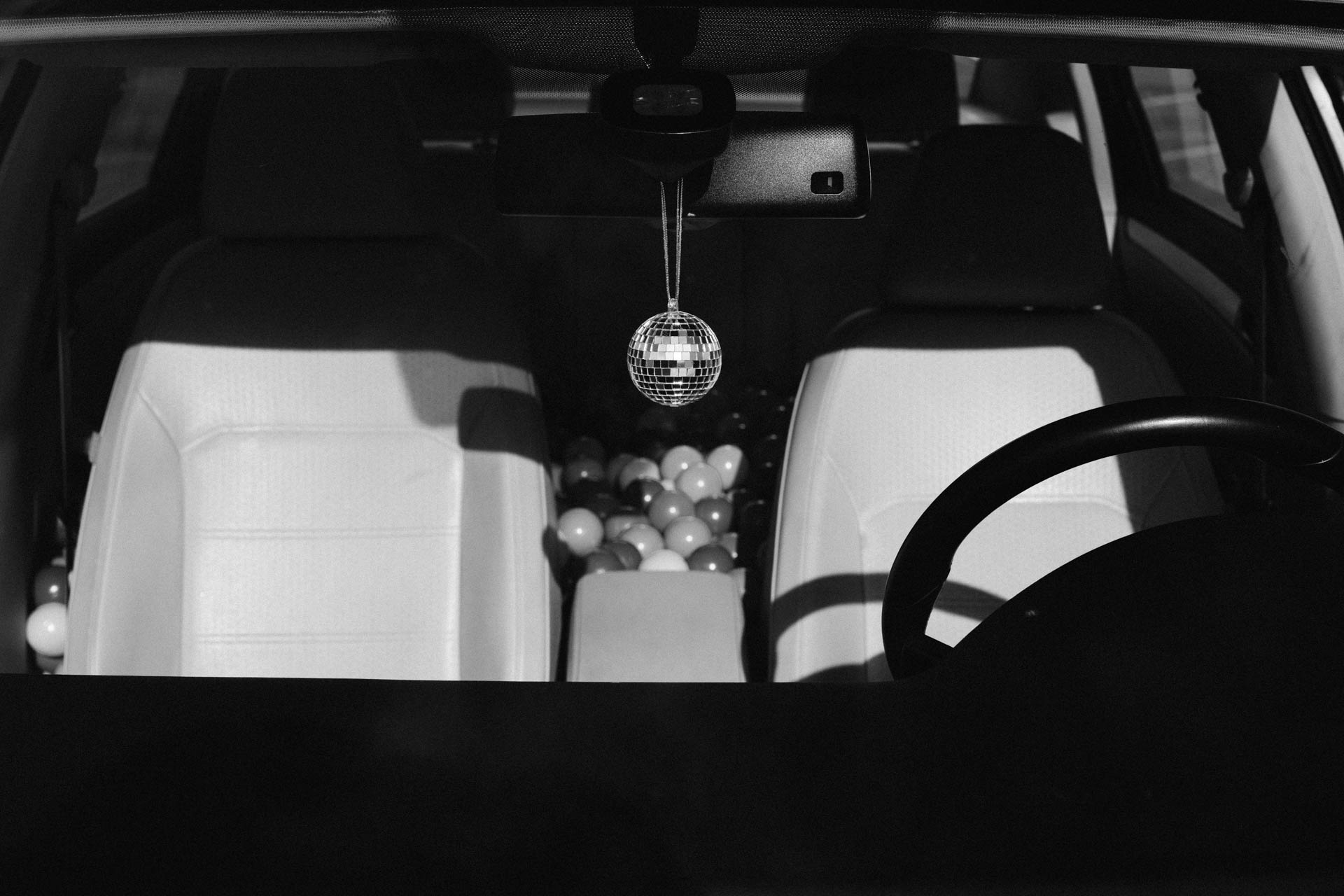 the interior of a car with a hanging disco ball ornament in black and white