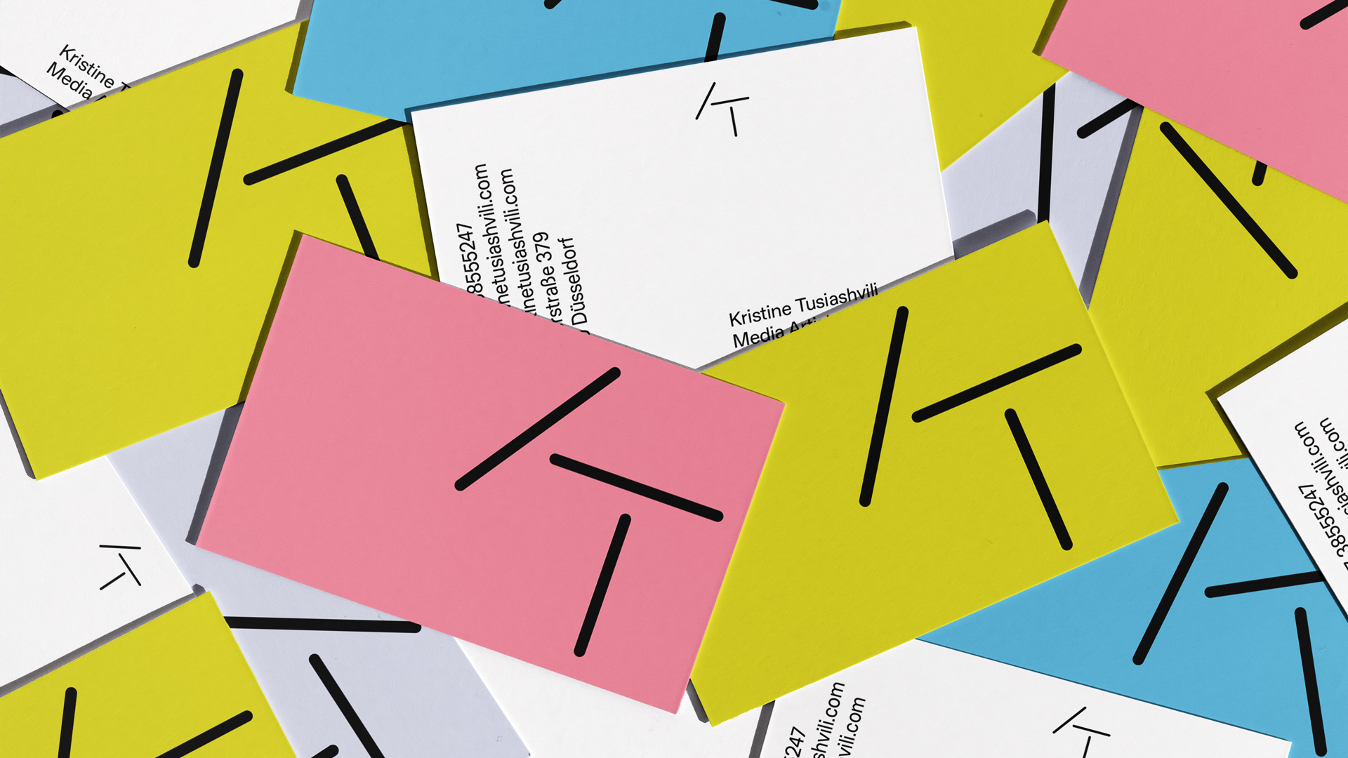 Bunte Visitenkarten mit schwarzem stilisiertem KT-Logo und Kontaktinformationen auf weißen Karten.