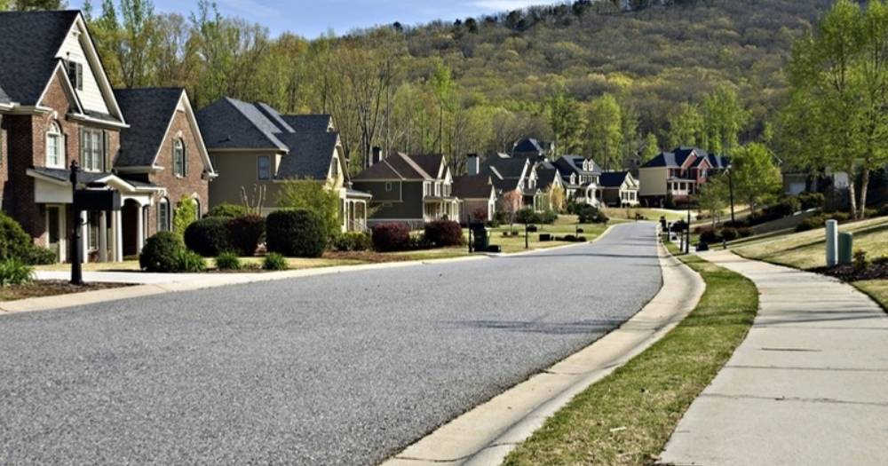Neighborhood street lined with brick homes below wooded hills in Middle Tennessee