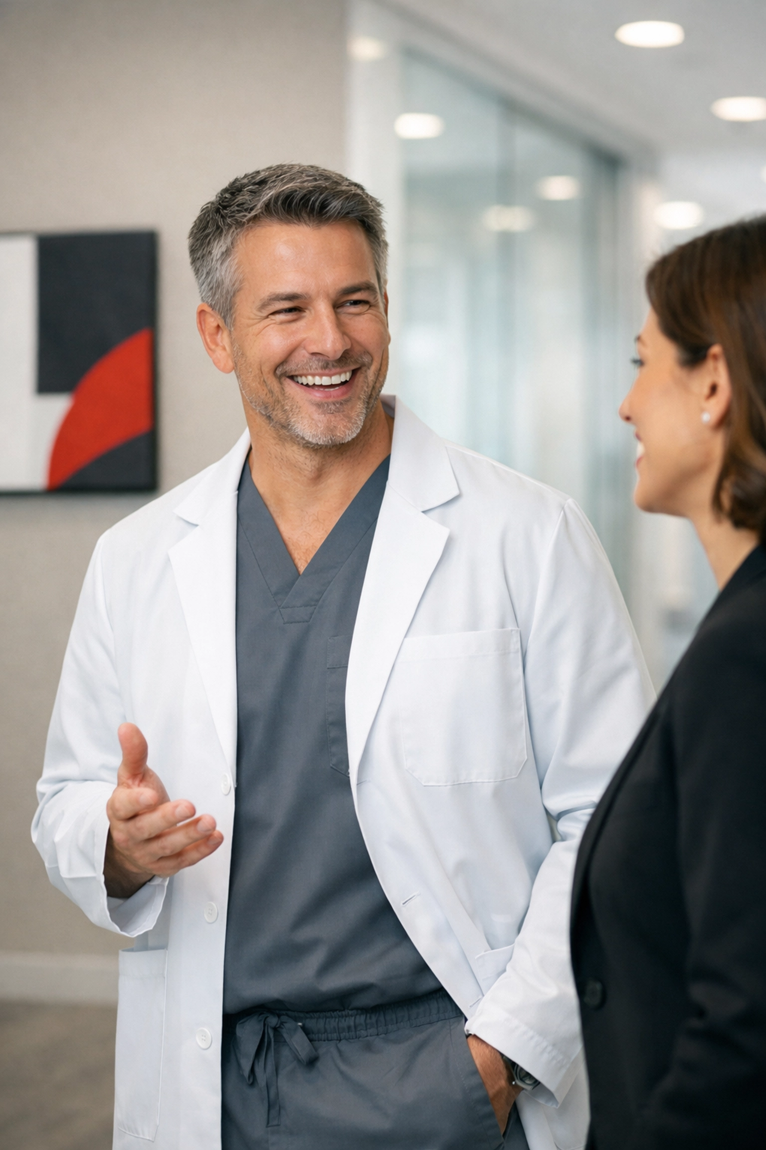 A professional dentist and colleague discussing clinic culture in a modern dental office hallway.