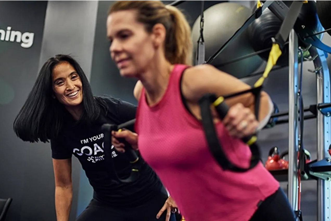 Two women exercising in a gym with resistance bands.