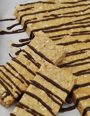 Oatmeal bars drizzled with chocolate, arranged on parchment paper, showcasing a delicious and healthy snack option.