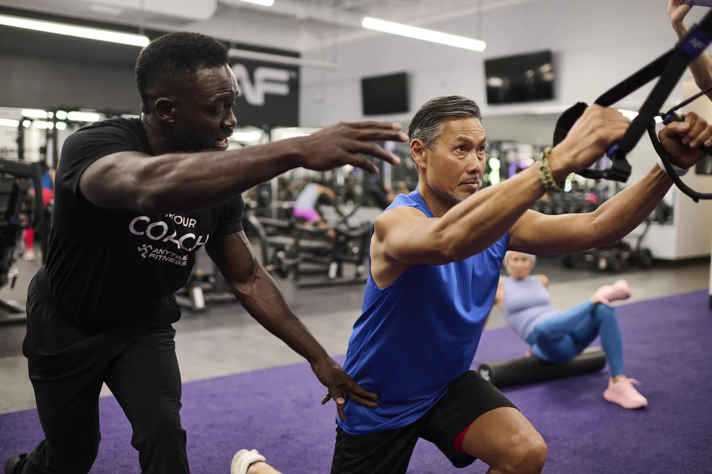 Woman exercising on treadmill at a gym with others in the background