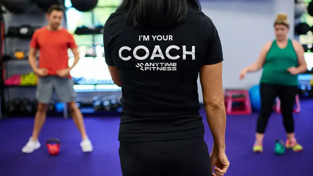Fitness coach in black shirt at gym with text "I'm your coach"