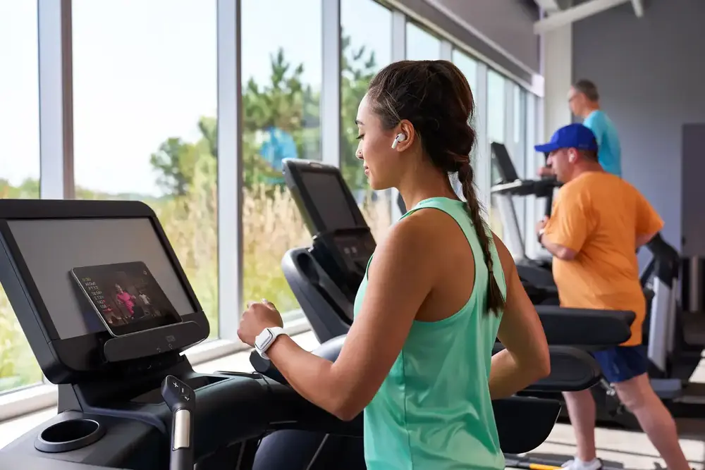 Woman exercising on treadmill at a gym with others in the background