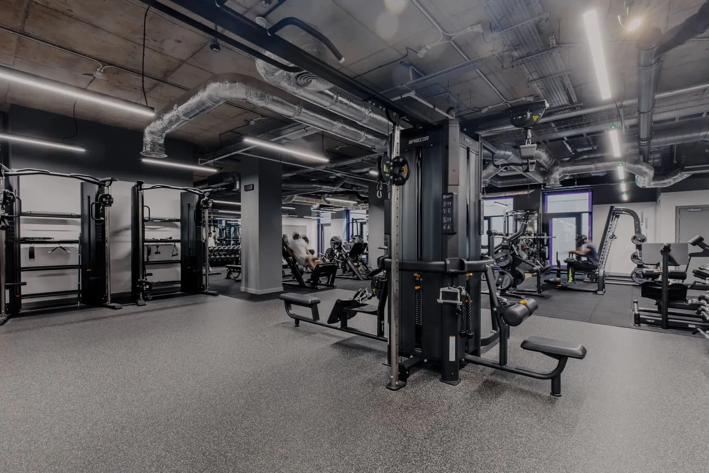 A modern gym interior featuring various workout equipment, including weight machines and benches, in a spacious and well-lit environment.