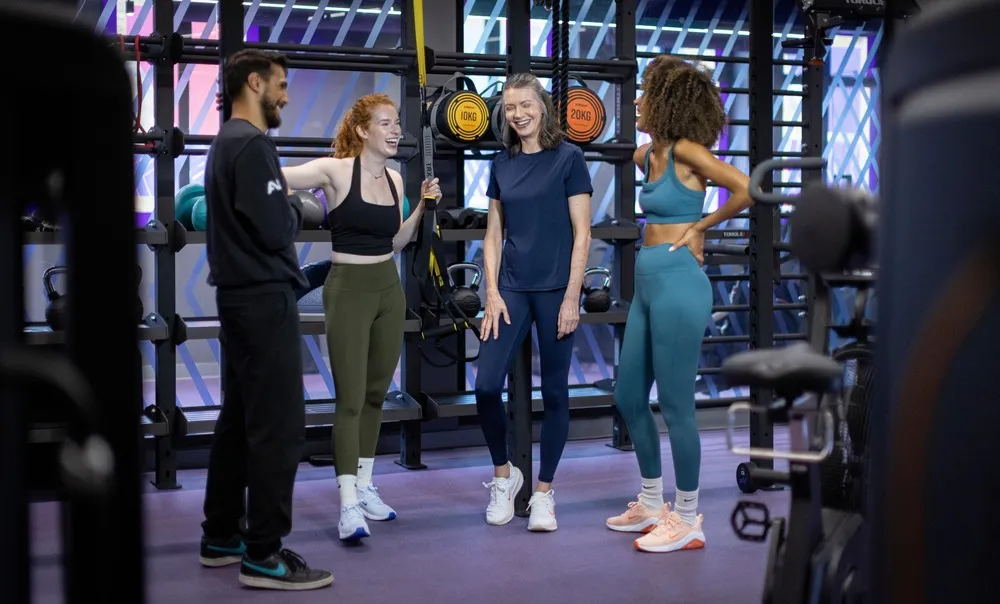 Personal trainer coaching a gym member on proper exercise form while seated on the gym floor.
