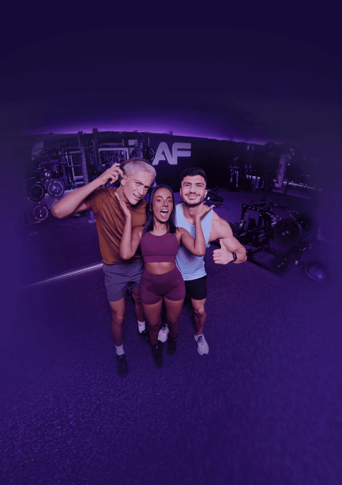 A personal trainer smiles while supervising a woman performing a dumbbell chest press on a weight bench in a modern gym.
