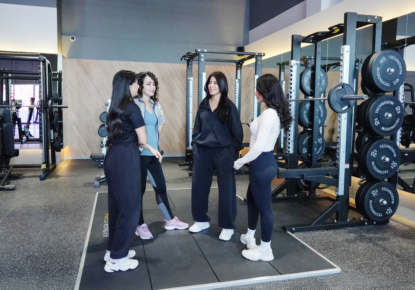 مجموعة من النساء يتحدثن مع مدربة على أرضية الجيم في Anytime Fitness