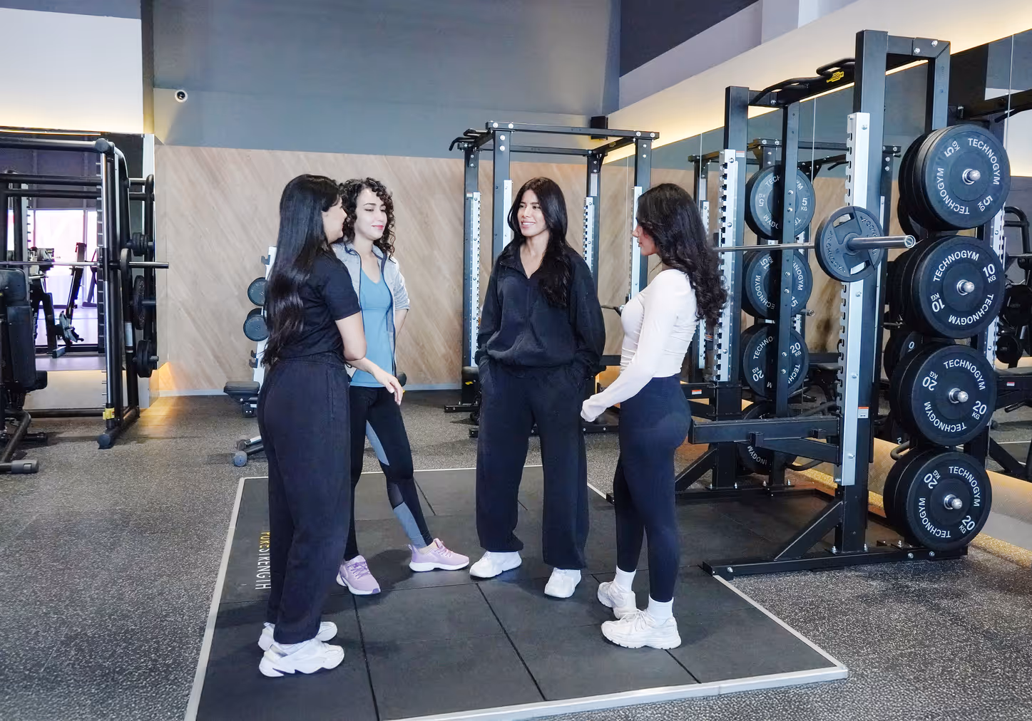 مجموعة من النساء يتحدثن مع مدربة على أرضية الجيم في Anytime Fitness