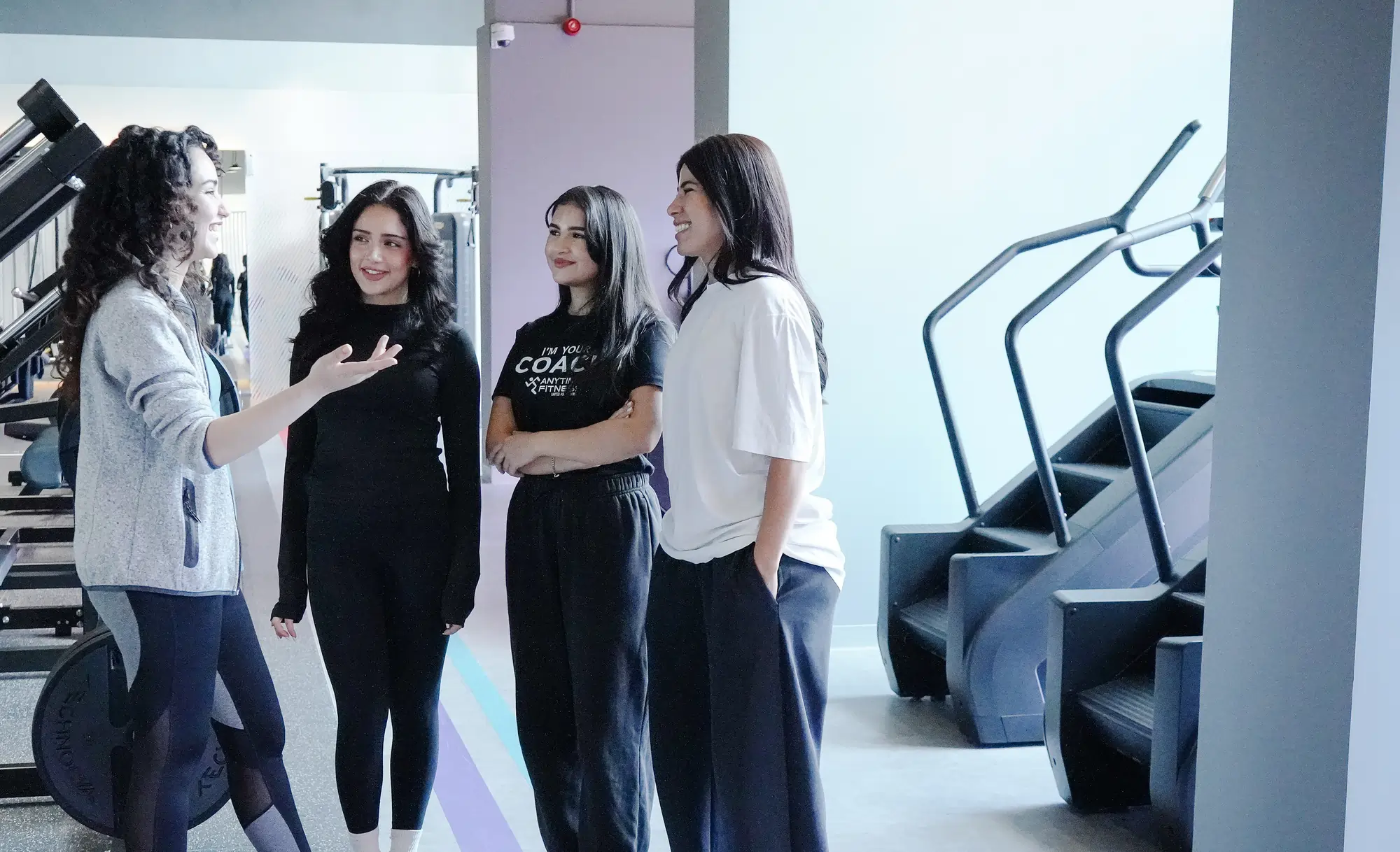 مدربة توجه مشترِكة أثناء استخدام جهاز الكابل في Anytime Fitness