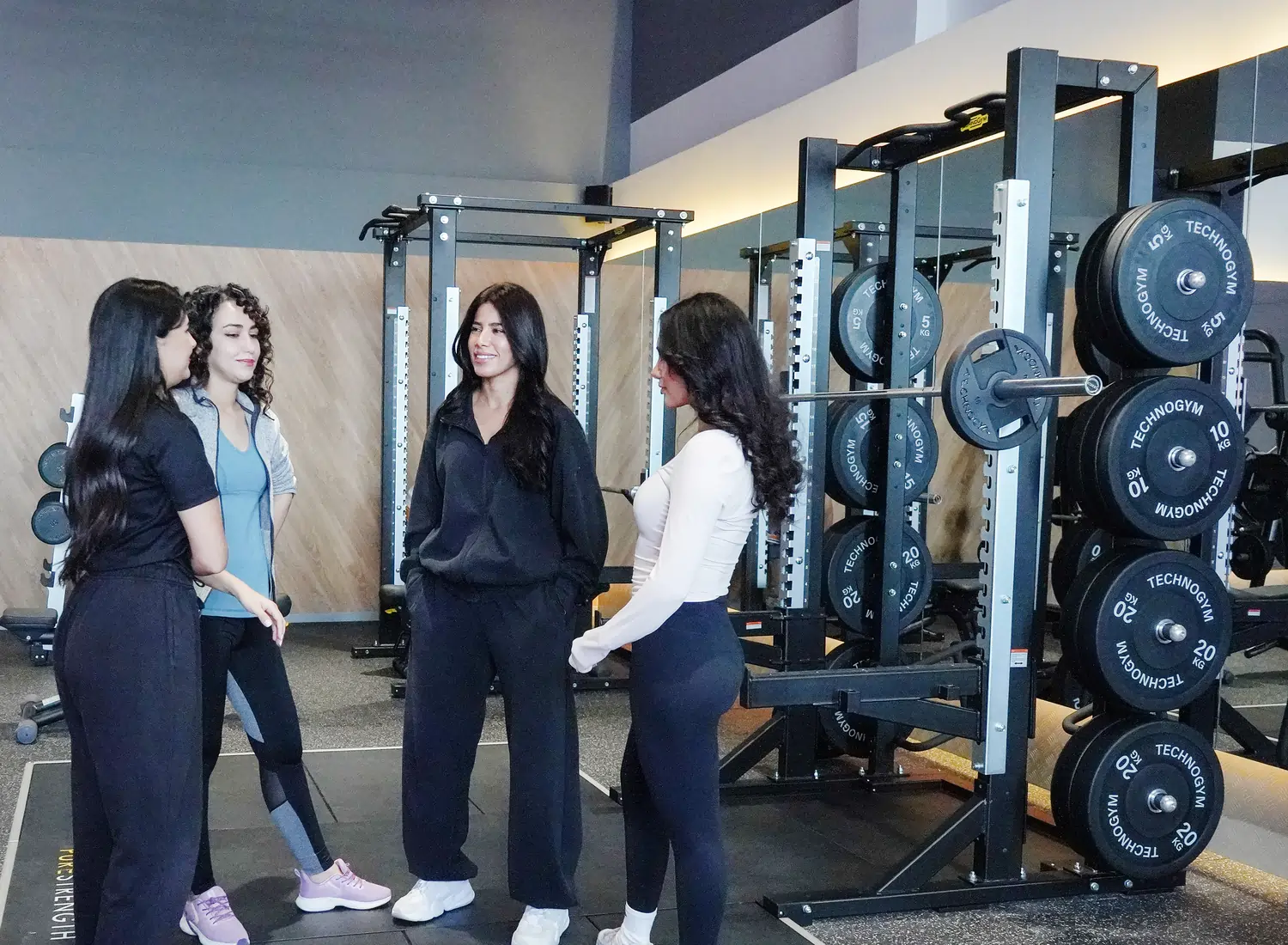 مجموعة من النساء يتحدثن مع مدربة على أرضية الجيم في Anytime Fitness