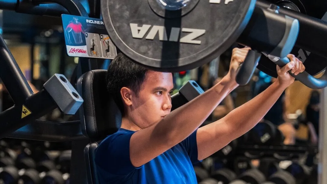 Man performing incline chest press exercises on a plate-loaded gym machine.