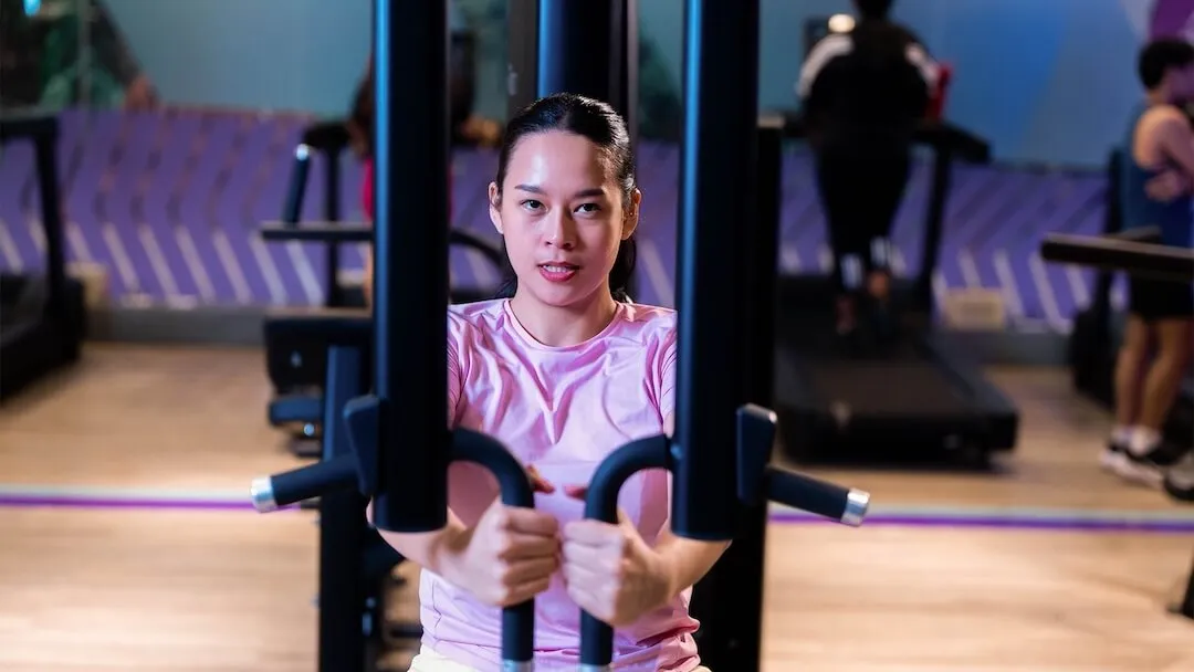 Woman using a chest fly strength machine in a gym.