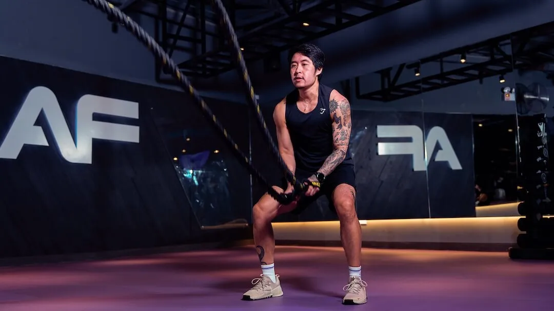 Male member performing heavy battle rope exercises in the Anytime Fitness functional training area.