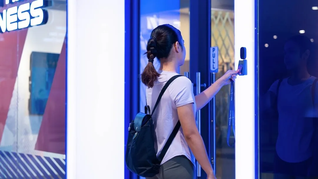 Female member scanning her key fob for 24/7 access at the Anytime Fitness entrance door.