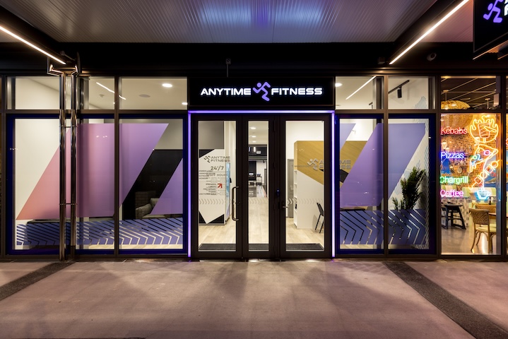 Front entrance of an Anytime Fitness gym with glass doors and illuminated sign at night.