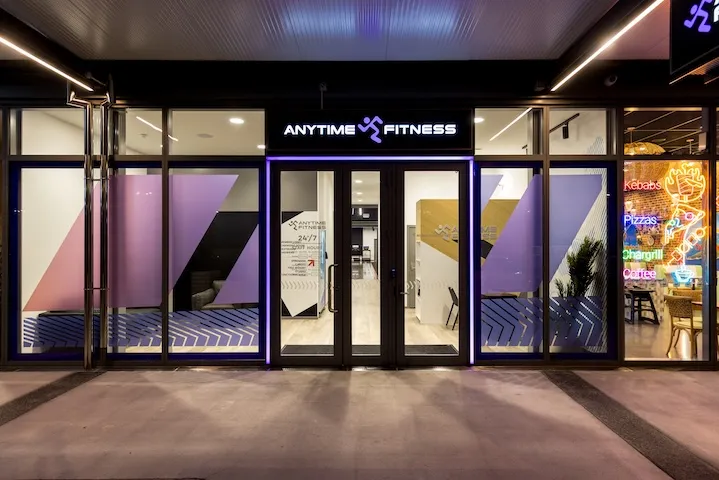 Front entrance of an Anytime Fitness gym with glass doors and illuminated sign at night.