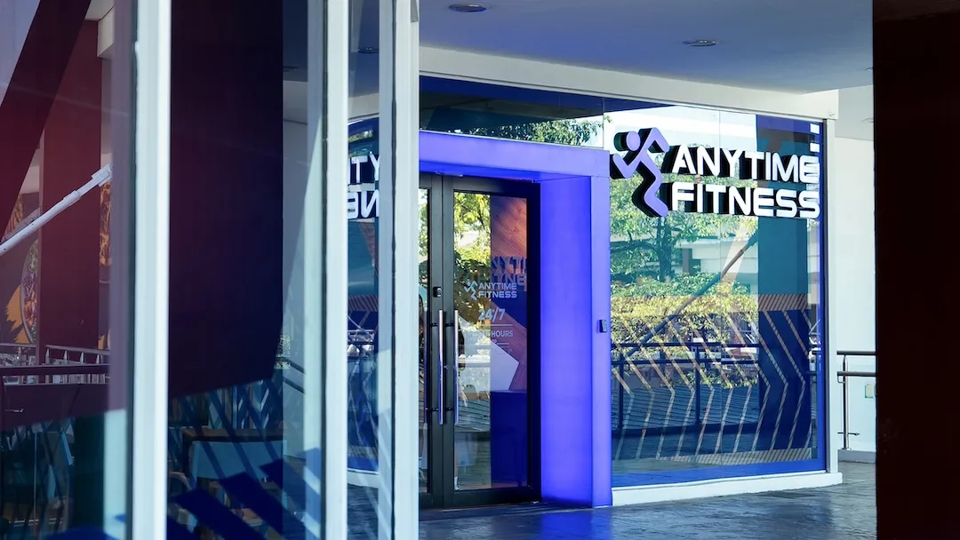 Exterior entrance of an Anytime Fitness gym featuring an illuminated purple doorway and brand logo