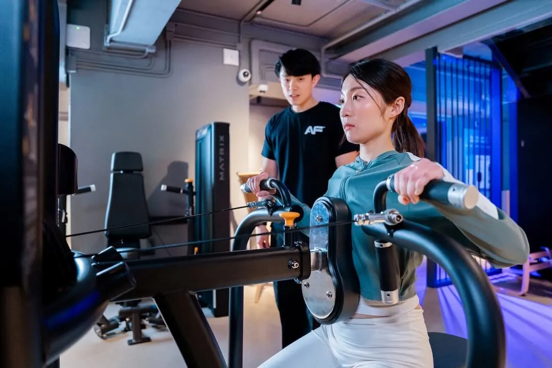 女會員在 Anytime Fitness 私人教練指導下使用健身器材