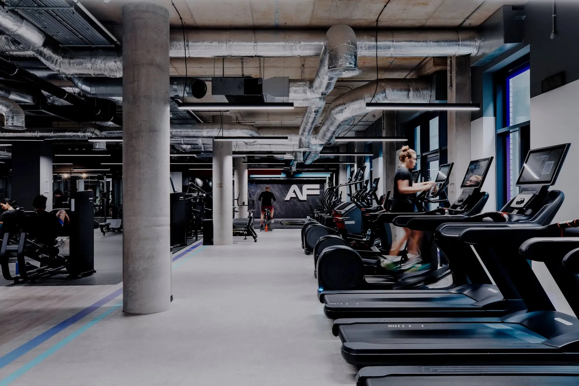 Modern Anytime Fitness gym interior featuring cardio machines and members training