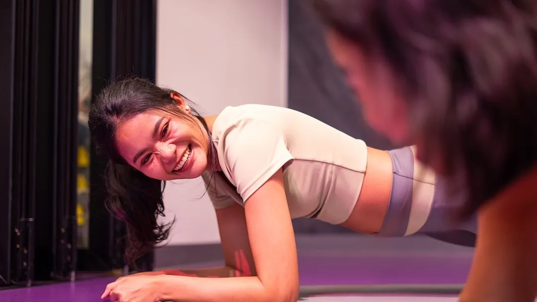 สมาชิกหญิงยิ้มสดใสขณะทำท่าแพลงก์ (Plank) ฝึกแกนกลางลำตัว