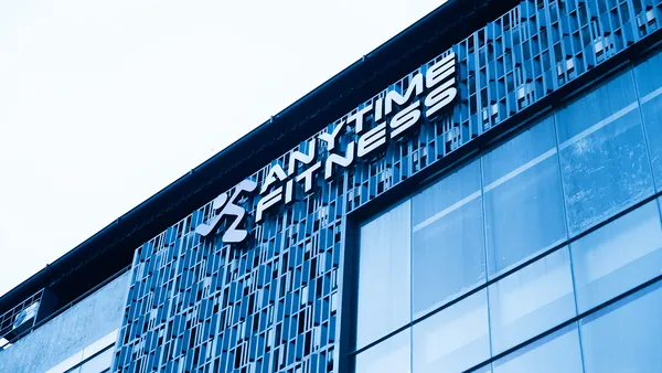 Eksterior bangunan modern dengan logo Anytime Fitness pada fasad bermotif biru.