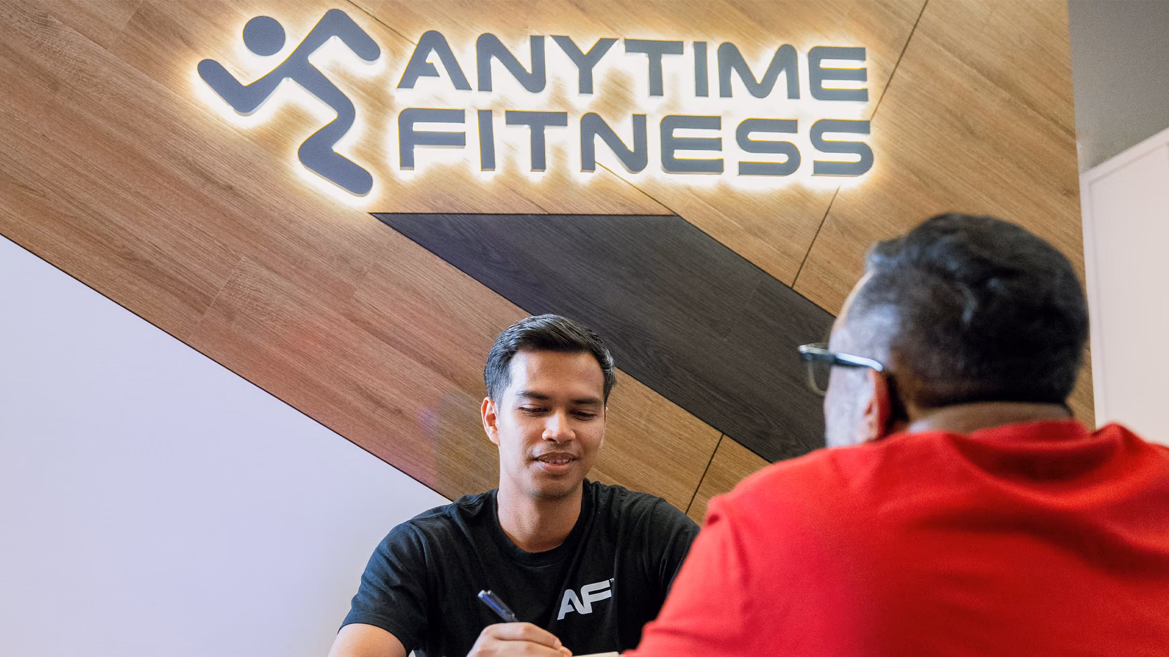 Fitness consultation at Anytime Fitness, with a coach and member seated at a round table