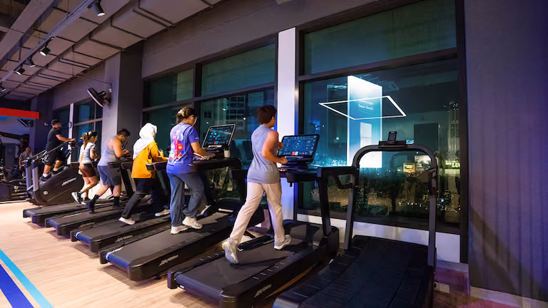 Group of gym members entering an Anytime Fitness club with a welcoming neon sign