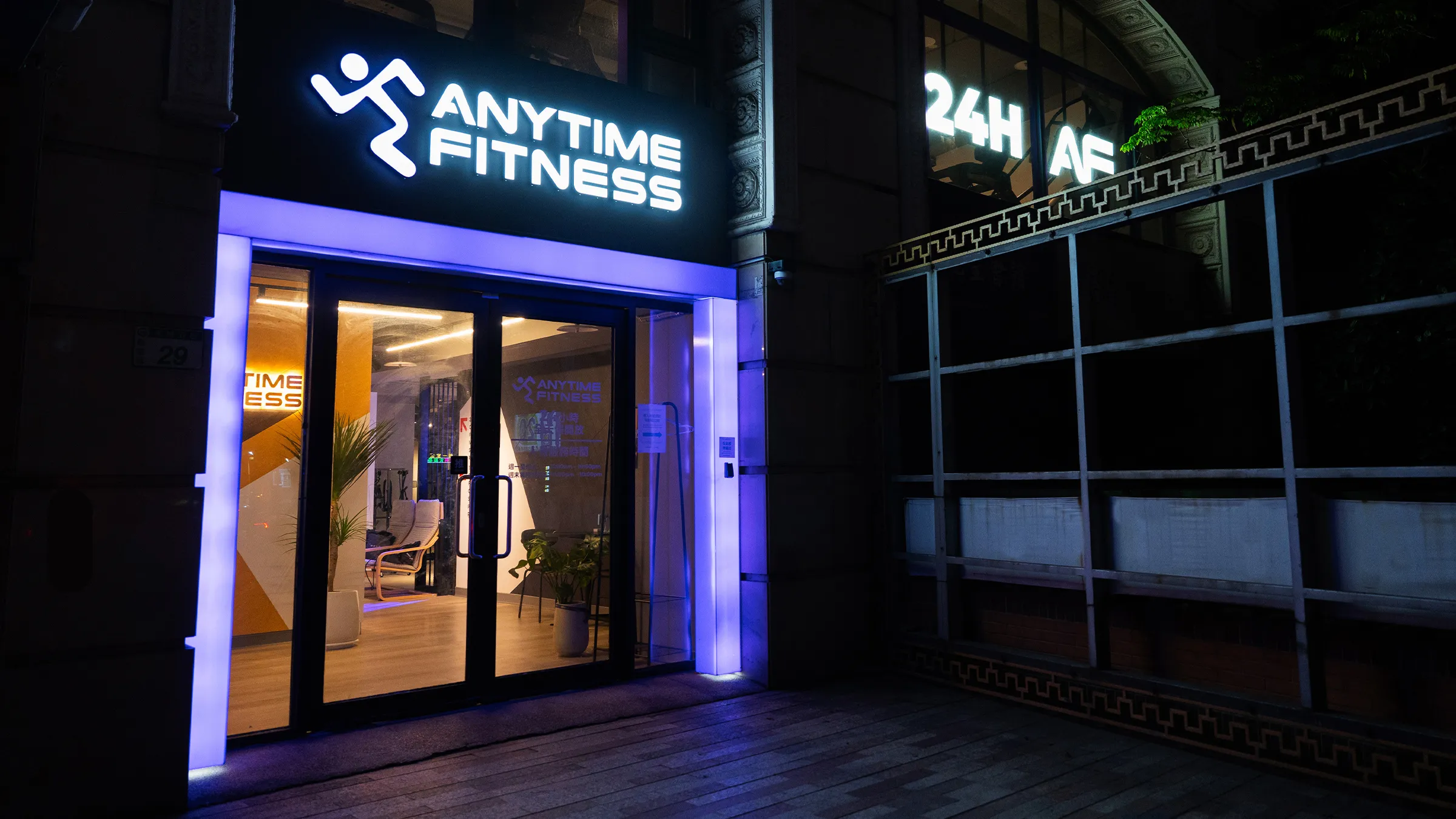 Anytime Fitness 健身房的夜間入口,帶有照明標誌和玻璃門。
