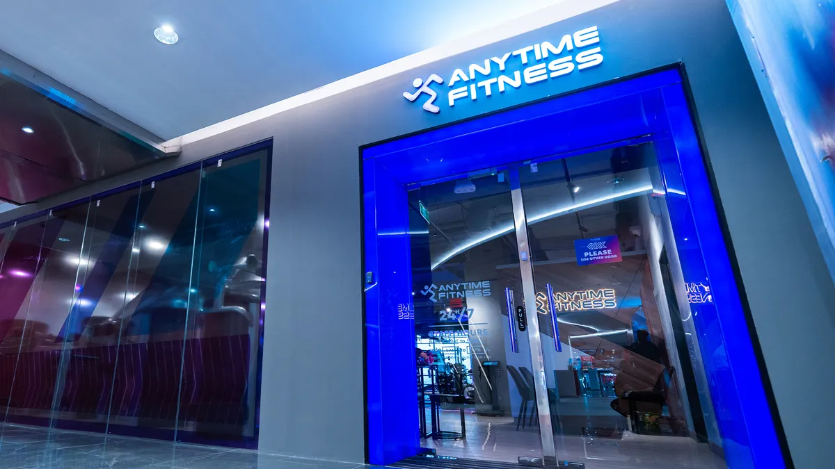 Front entrance of an Anytime Fitness gym with blue lighting and glass doors.