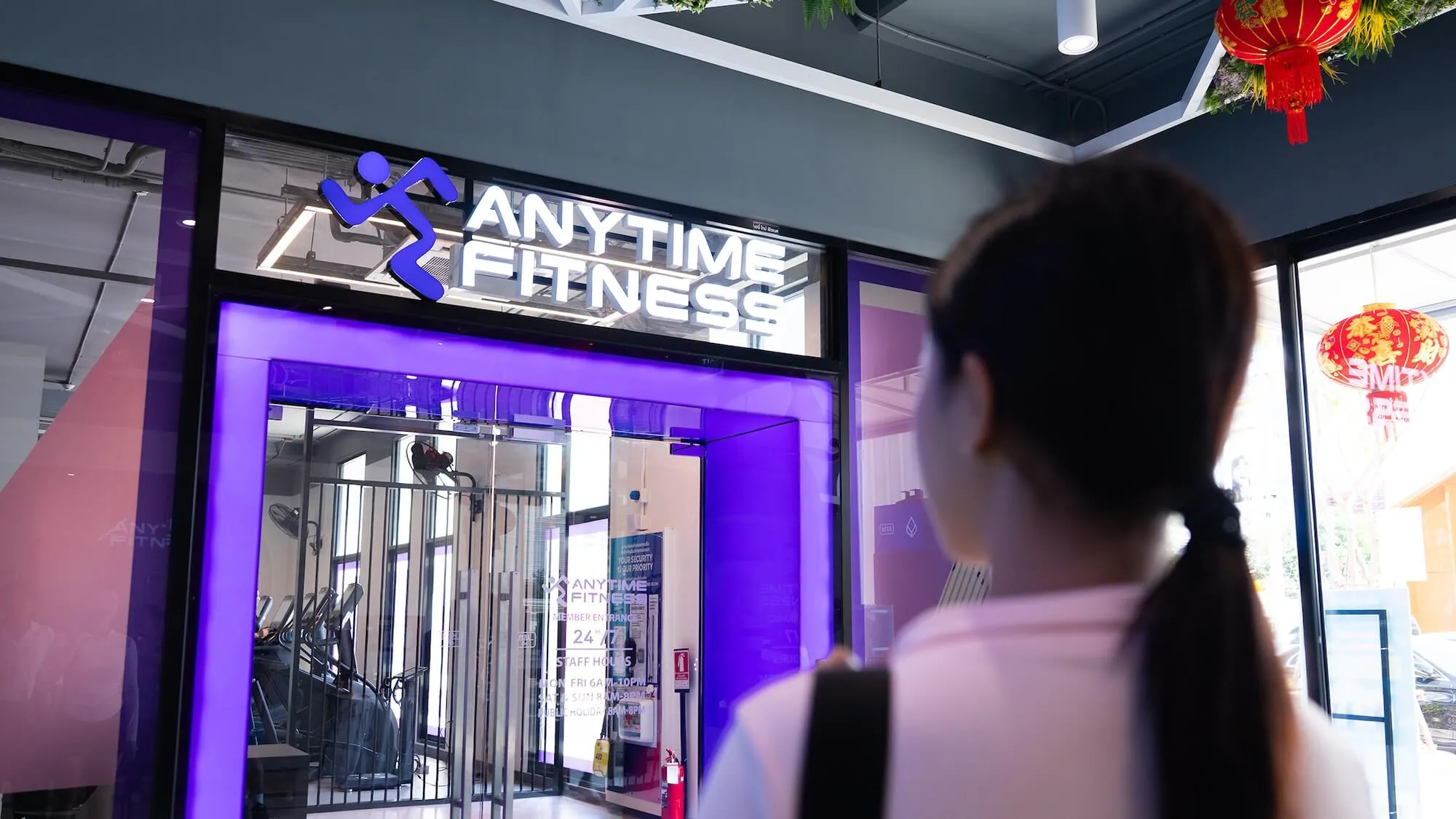 ทางเข้าฟิตเนส Anytime Fitness พร้อมป้ายชื่อแบรนด์และประตูไฟสีม่วง