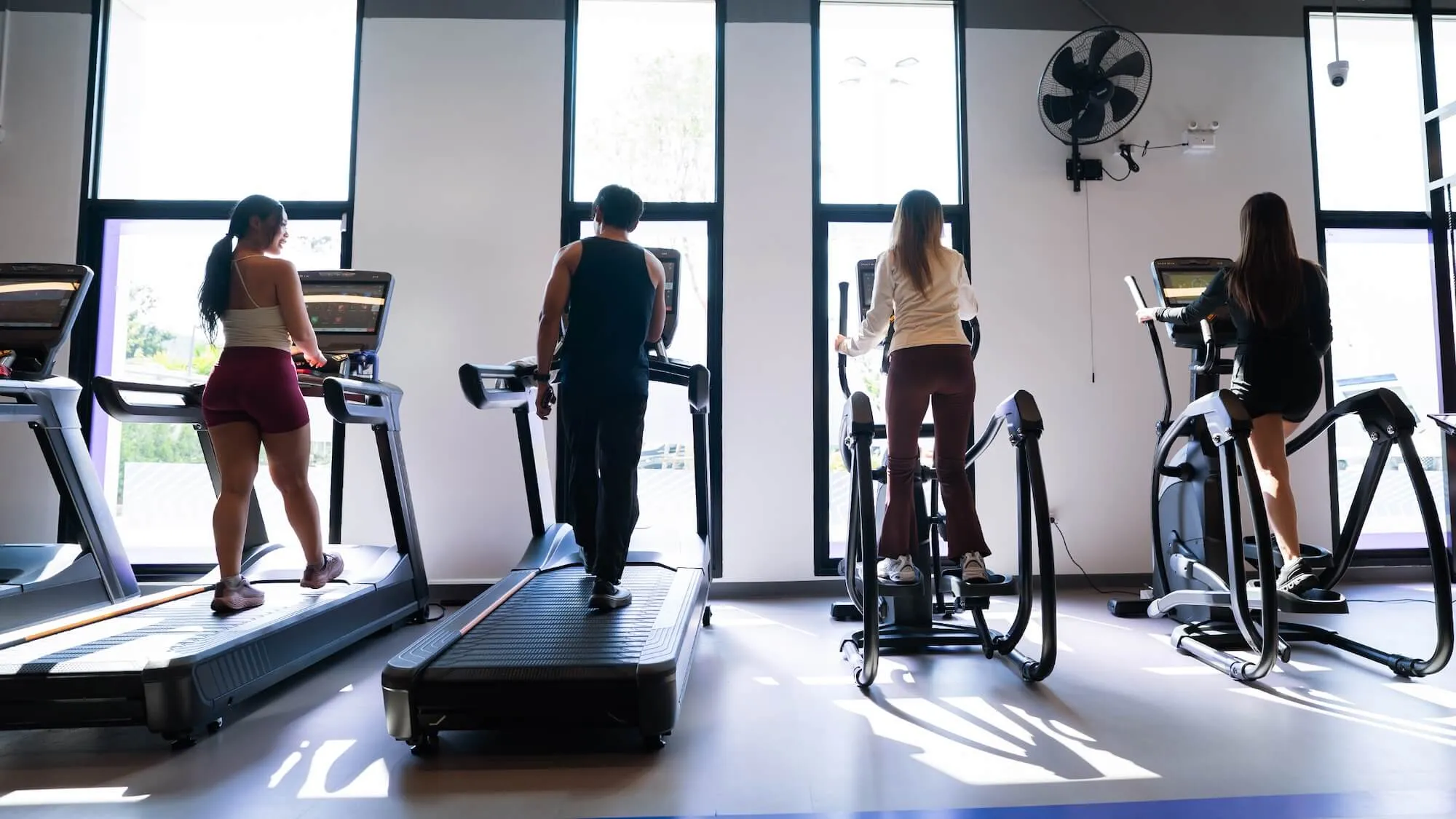 สมาชิกกำลังออกกำลังกายบนลู่วิ่งและเครื่องเดินวงรีในโซนคาร์ดิโอของ Anytime Fitness