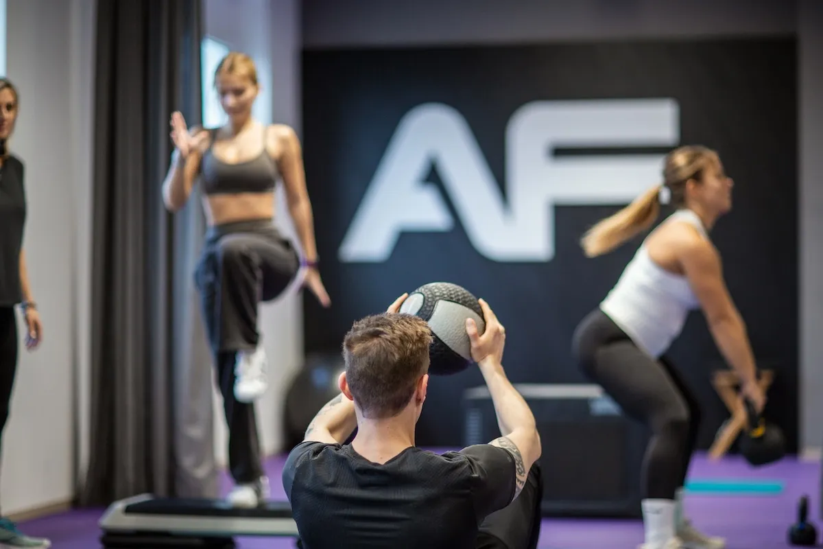 Functional-Fitness-Gruppe beim Training mit Medizinball und Step-Board vor dem AF-Logo.